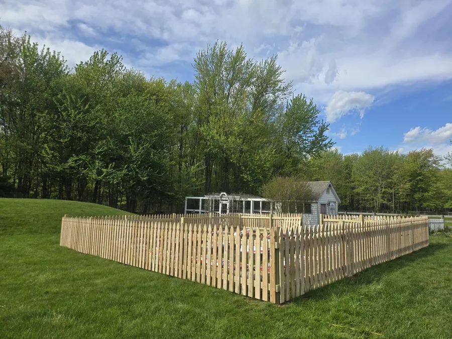 New wood picket fence enclosing a garden on a green lawn