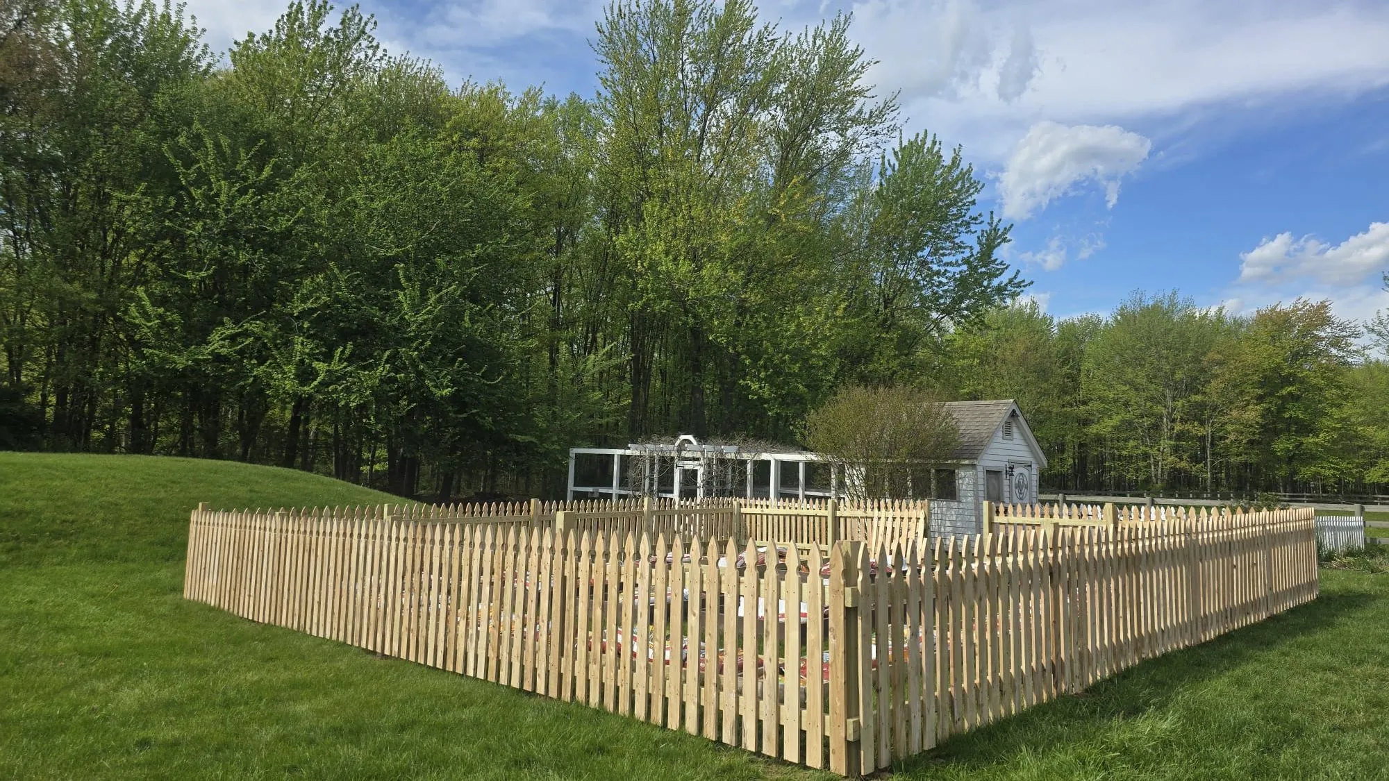 New wood picket fence enclosing a garden on a green lawn